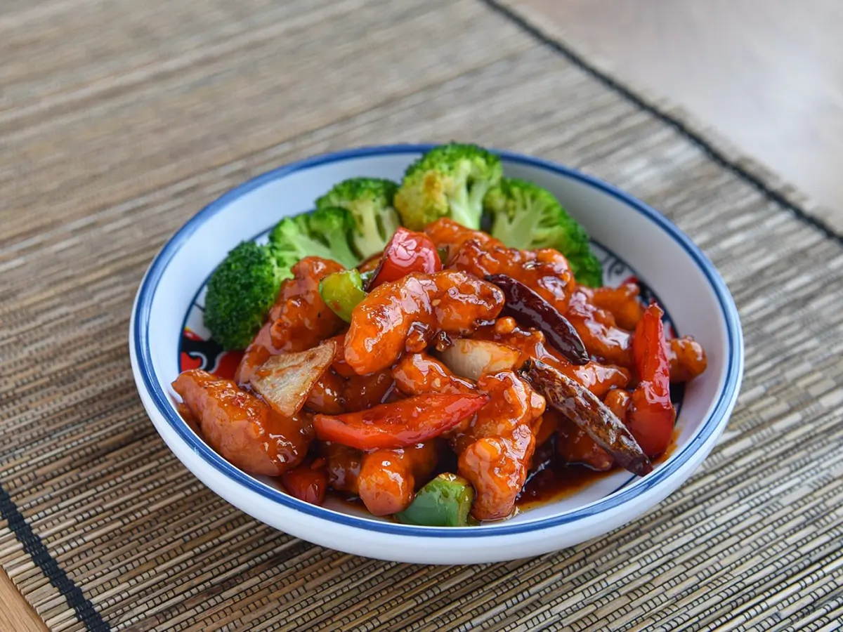 General Tso's Chicken features bite - sized chicken pieces stir - fried with peppers, onions, and dried chilies in a savory - sweet sauce at Dragon City, a Chinese restaurant in Albany